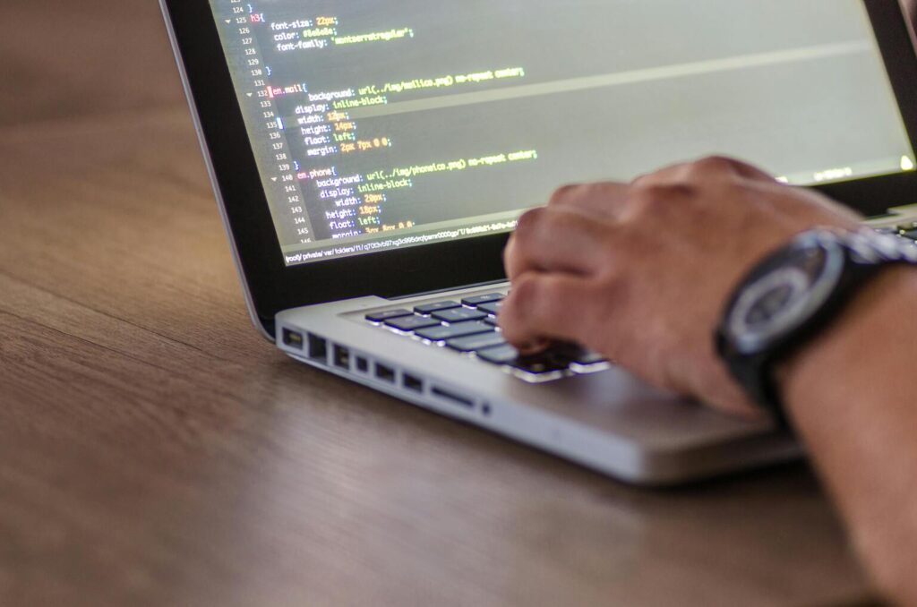 Zoom de 3/4 sur un laptop ouvert et la main d'un homme en train de taper sur le clavier. Un script de sécurité est affiché sur l'écran.