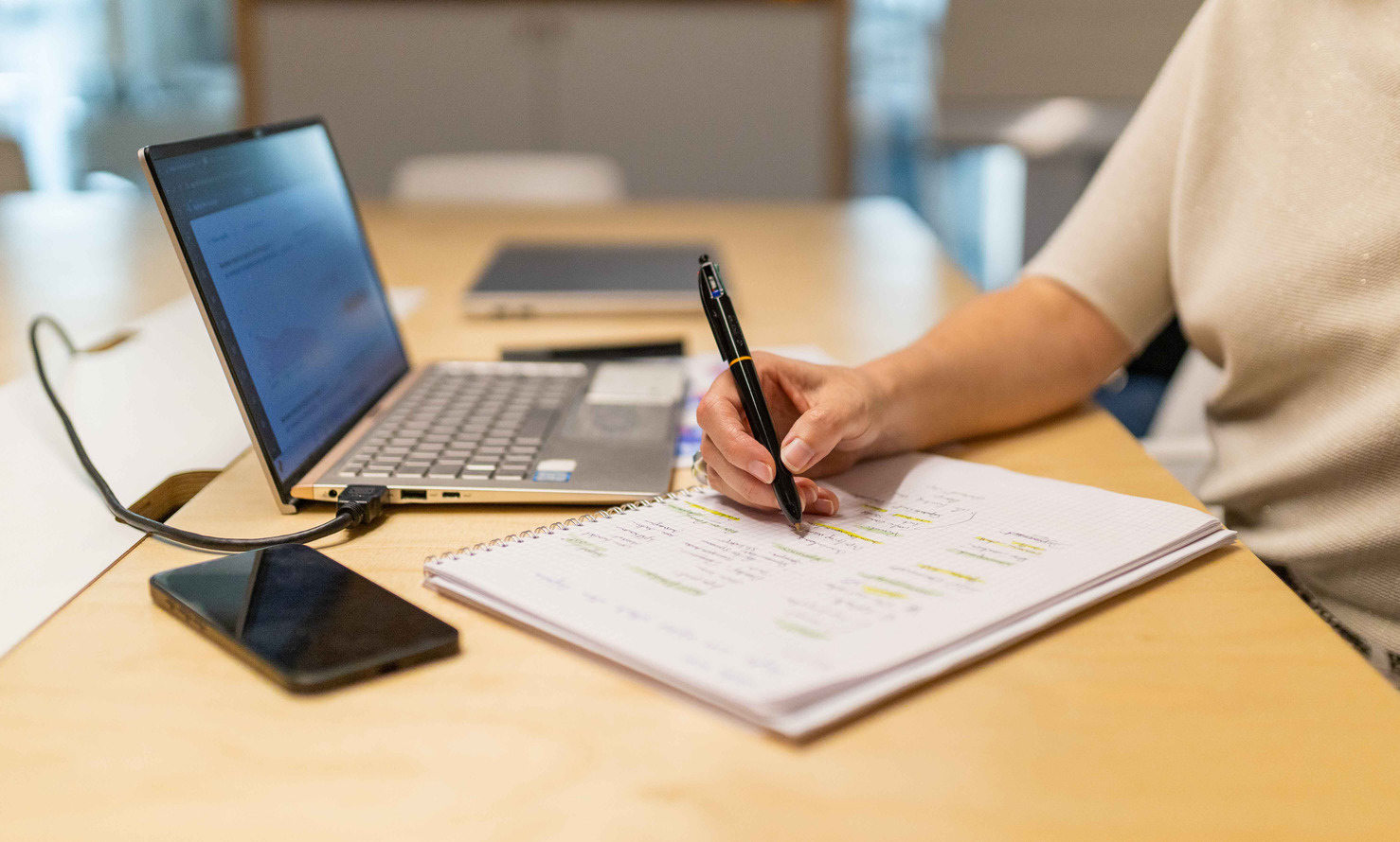 Gros plan sur une personne de l'équipe prenant des notes écrites assise devant son PC portable qui affiche les stocks de matériels chez les différents fournisseurs