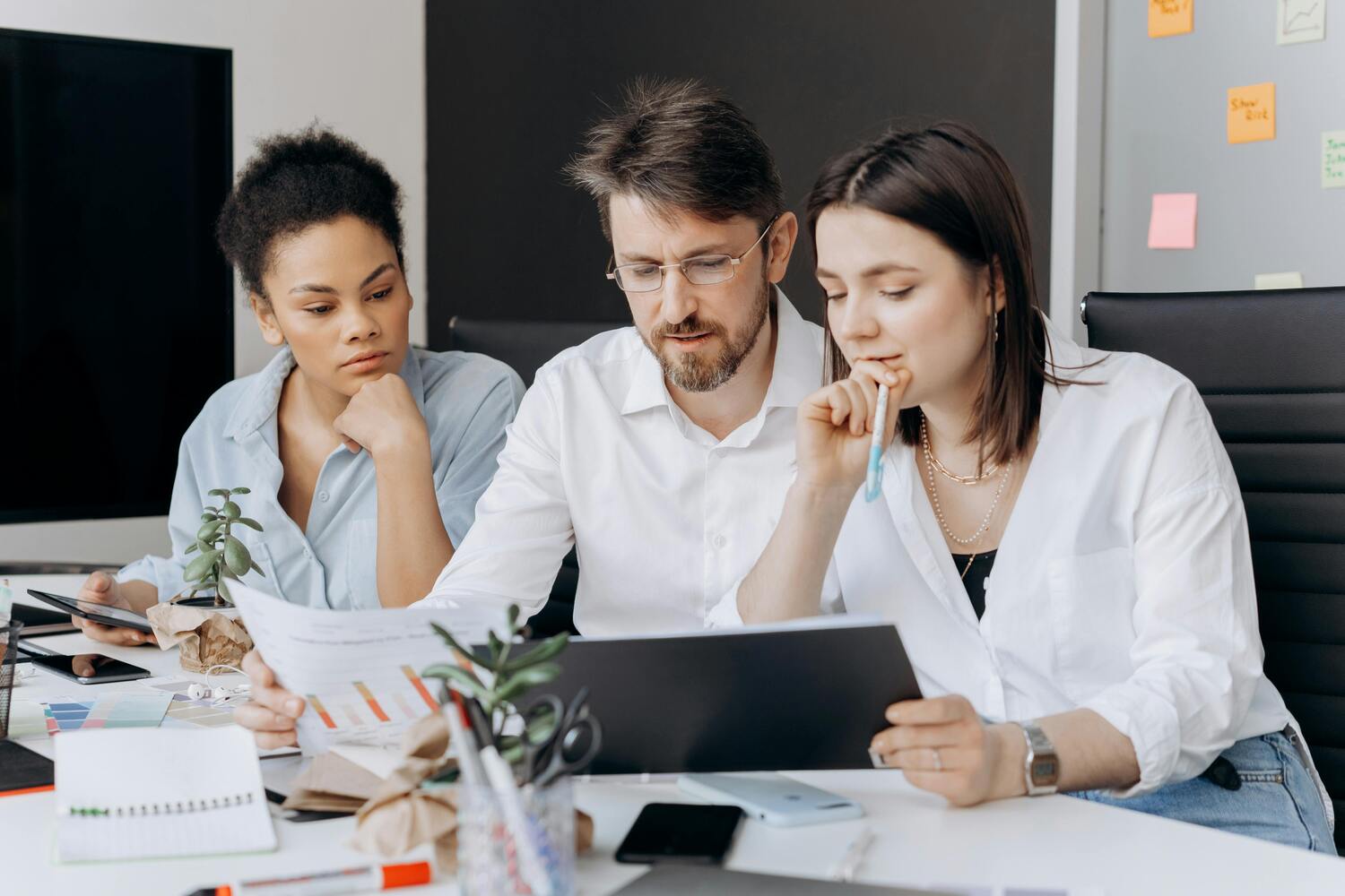 Léquipe d'une TPE lyonnaise est assise derrière un bureau pour travailler en collaboration depuis différents terminaux informatiques