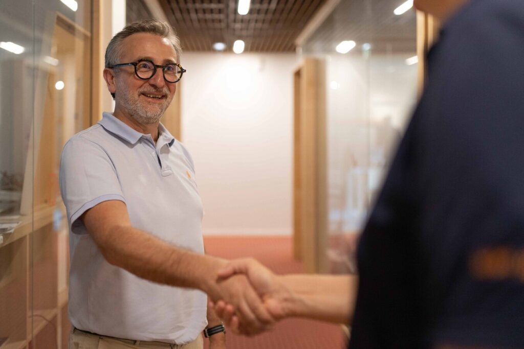 Le dirigeant de Kubs accueille avec le sourire un client en lui serrant la main