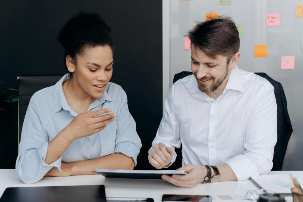 Deux employés d'une entreprise travaillent ensemble sur un document, assis derrière un bureau.