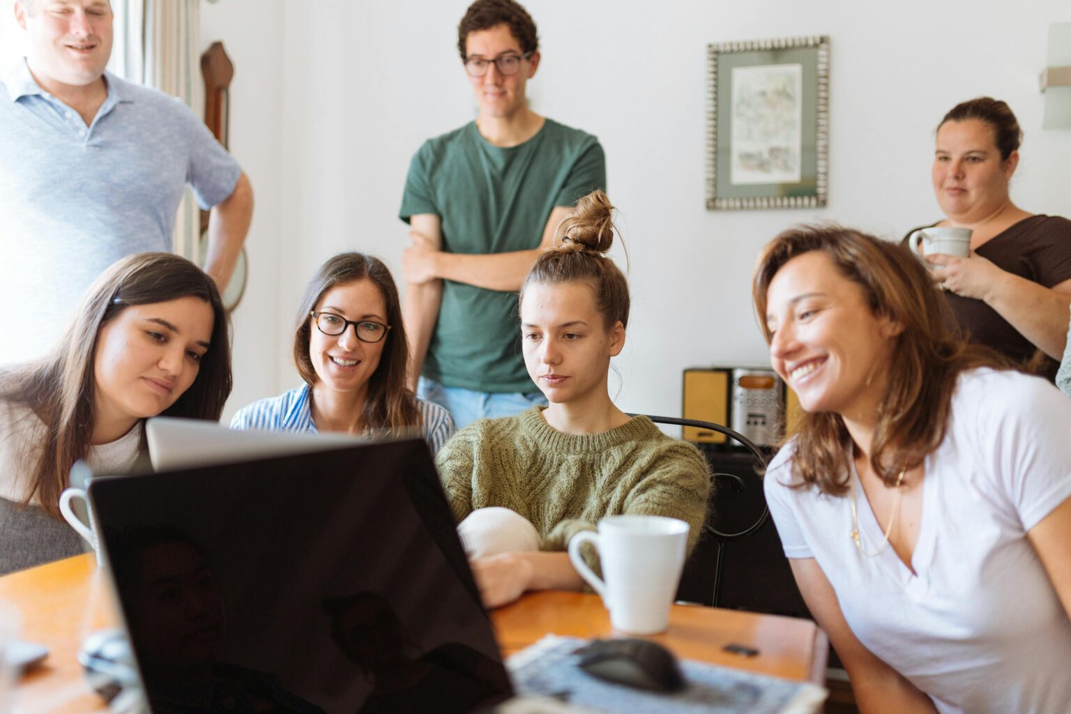 Une équipe de jeunes collaborateurs d'une entreprise lyonnaise est regroupée en salle de réunion et participent à une visioconférence. Ils sont souriant et attentifs.